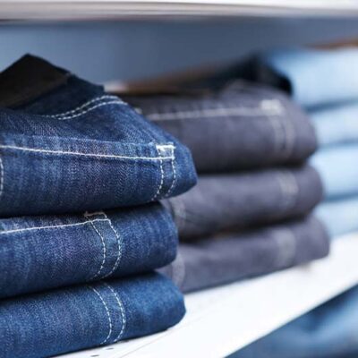 Stacks of neatly folded denim jeans on shelves in a store.