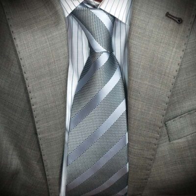 Close-up of a silver striped tie on a gray suit.