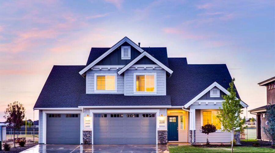 Modern two-story house with a three-car garage at sunset.