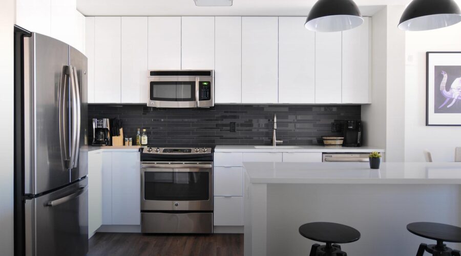 Modern kitchen with white cabinets and black backsplash.